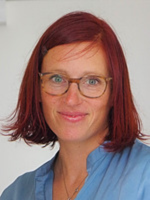 Frau mit kurzen, roten Haaren und blauer Bluse