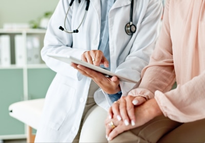 Medizinisches Fachpersonal erklärt einer Person etwas auf einem Tablet.