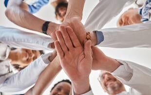 Mehrere Hände übereinander als Symbol für Teamarbeit.